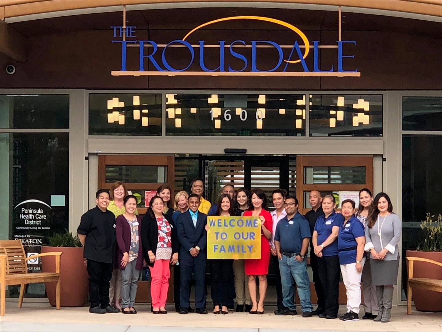 The Trousdale staff members holding a "Welcome to Our Family" sign